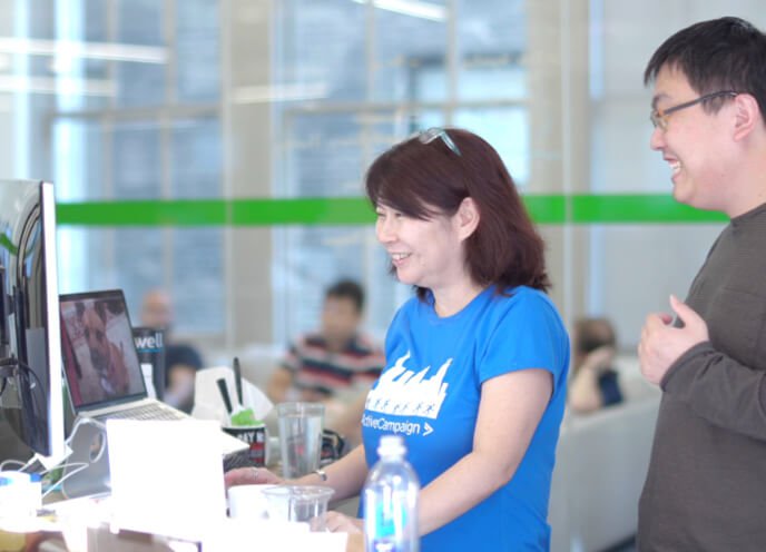 A man and a woman smiling and working together in front of computers